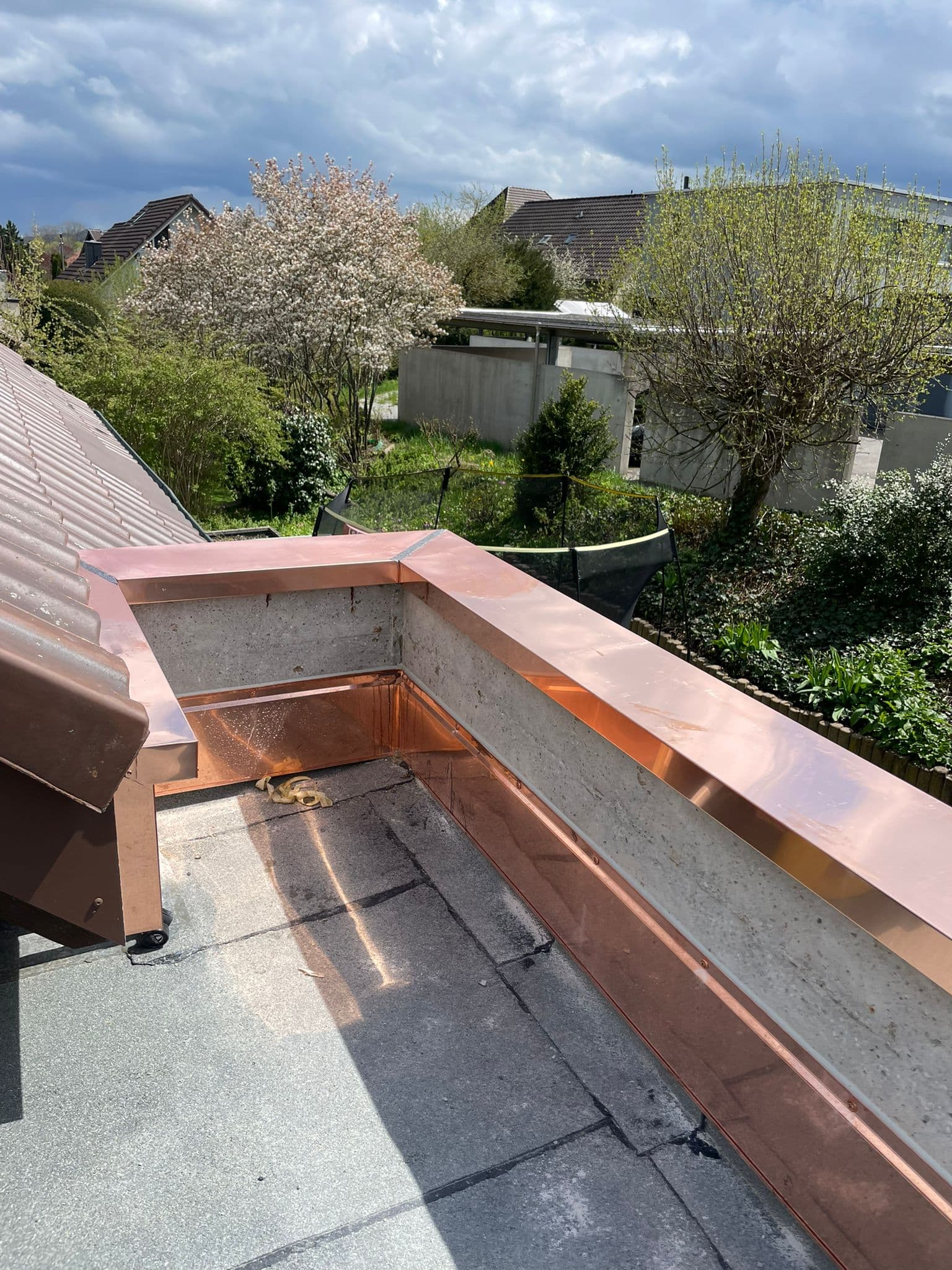 Neue Kupfer-Attika auf Flachdach mit Kirschblüten im Hintergrund