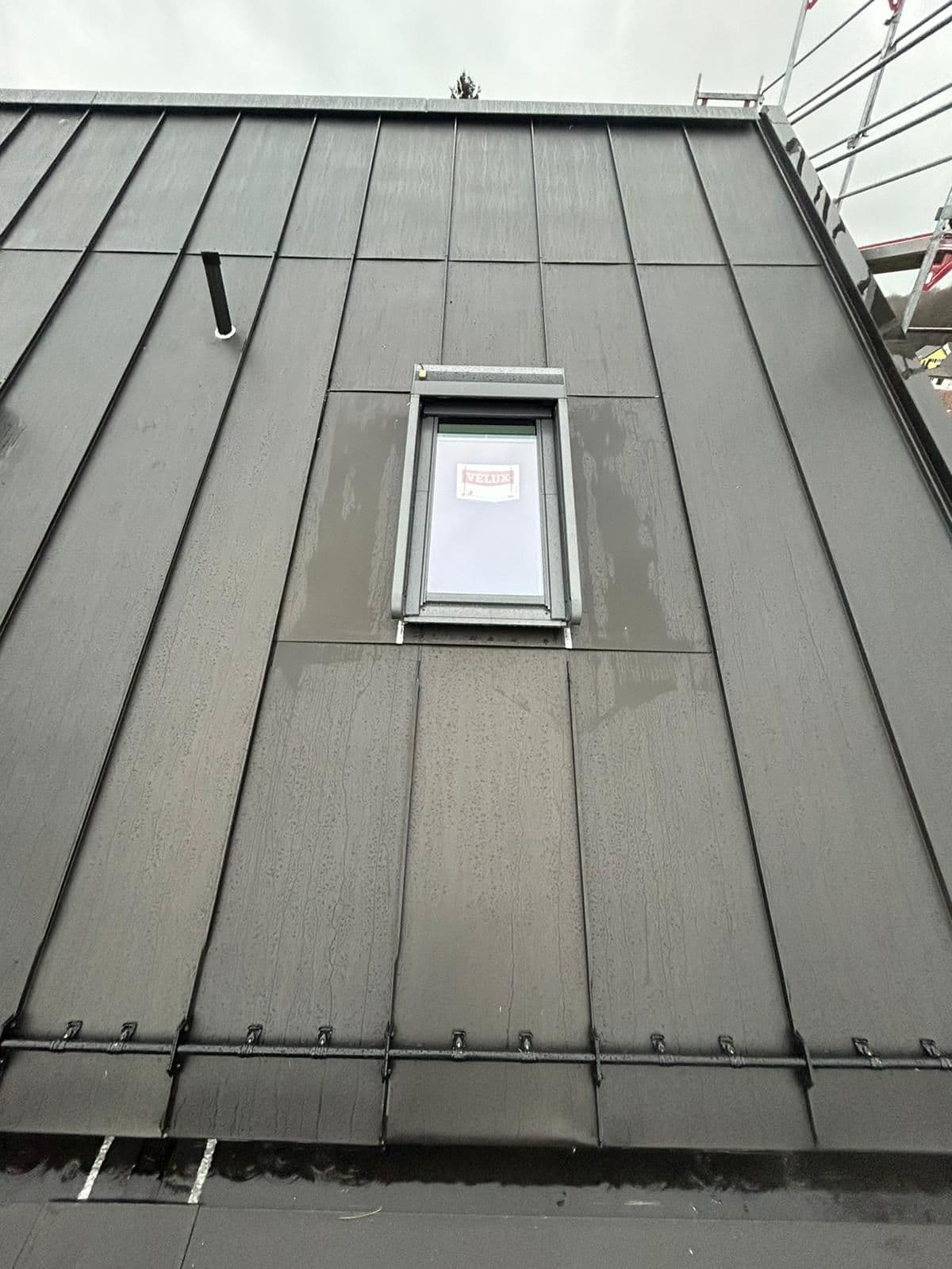 Anthrazitfarbene Stehfalzfassade mit Velux-Dachfenster
