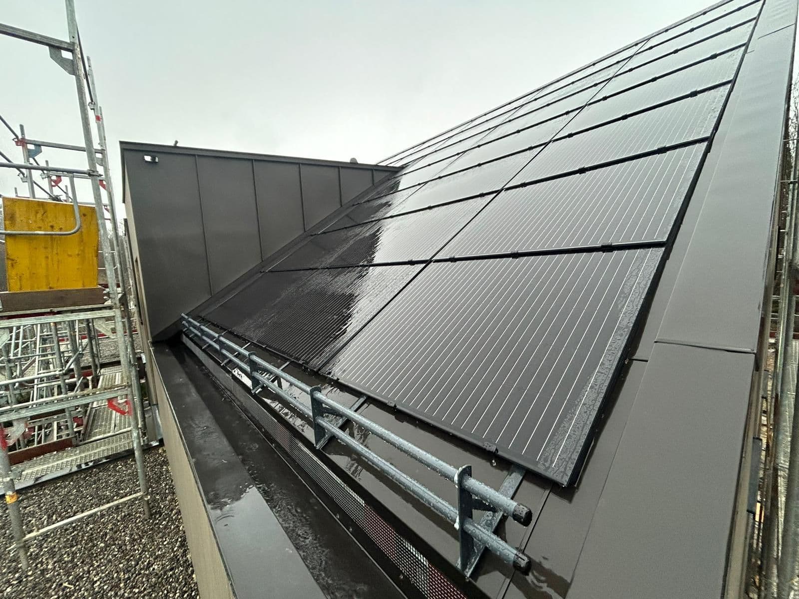 Anthrazitfarbene Metallfassade mit Indach-Solarintegration